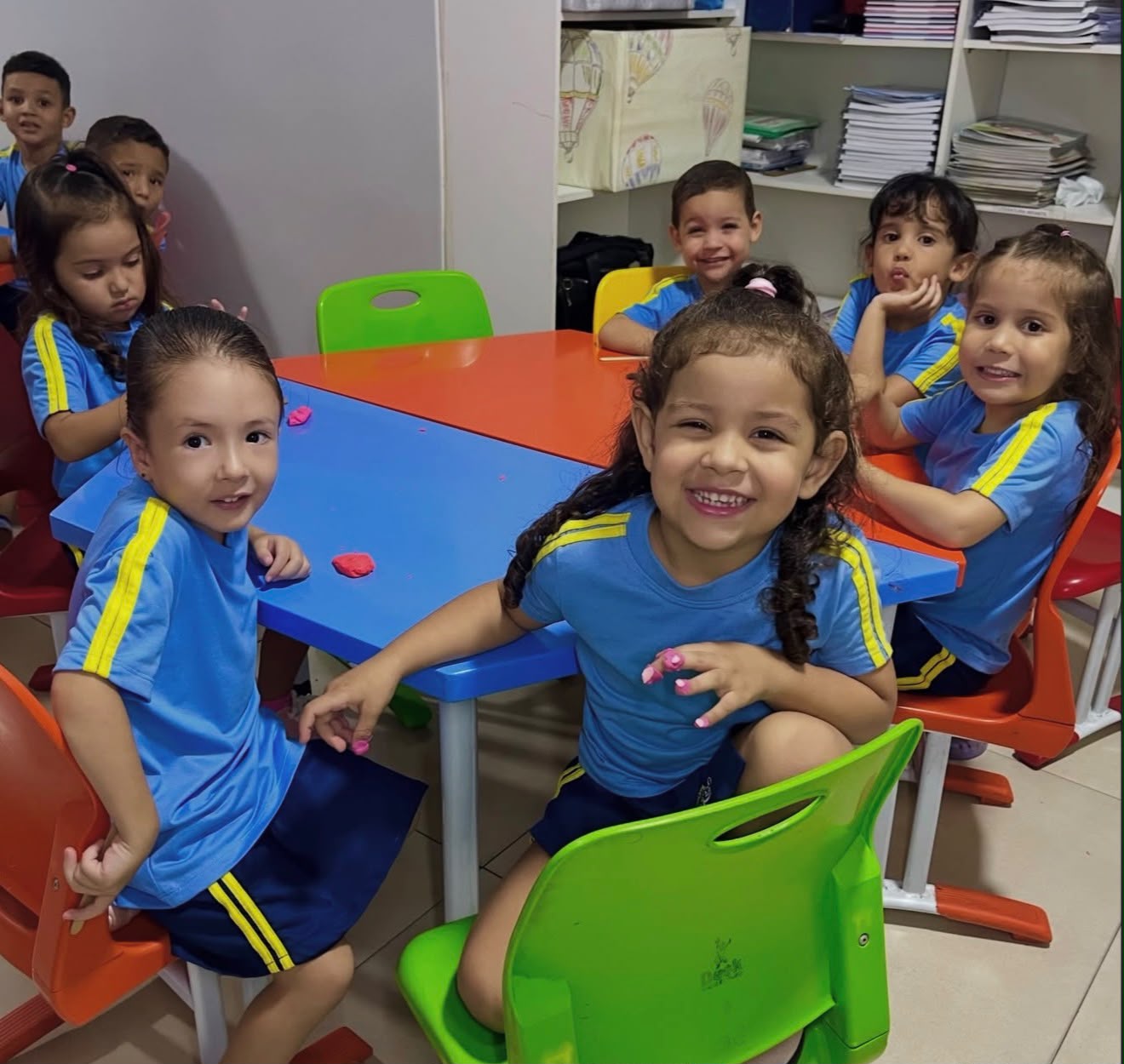 Crianças da educação infantil em atividade com massinha nas mesinhas coloridas