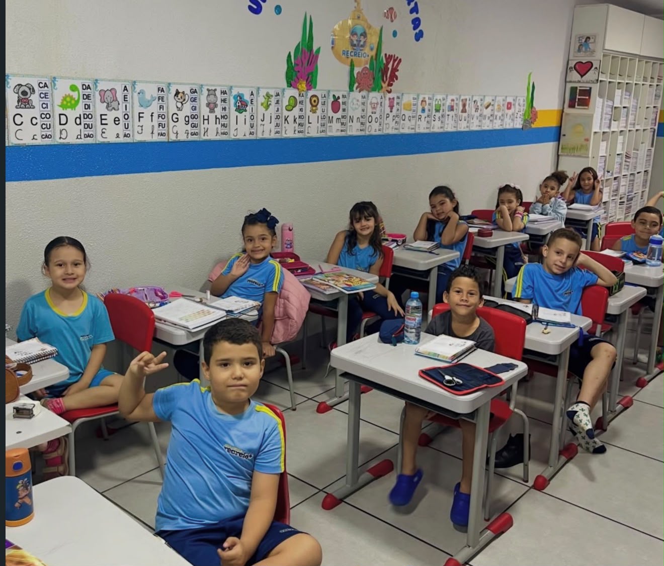Turma do ensino fundamental em sala de aula com alfabeto na parede