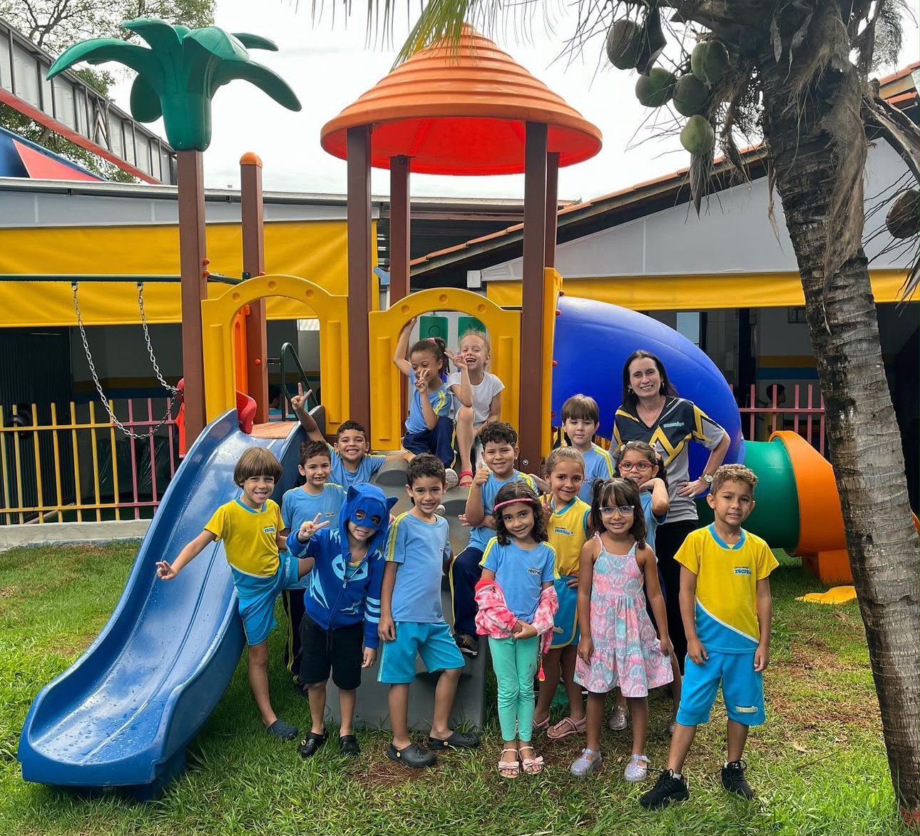 Crianças reunidas no parque com escorregador e playground da escola