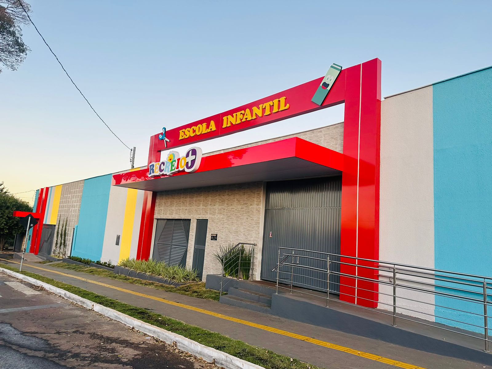 Fachada da Escola Infantil Recreio+ com pórtico vermelho e letreiro colorido