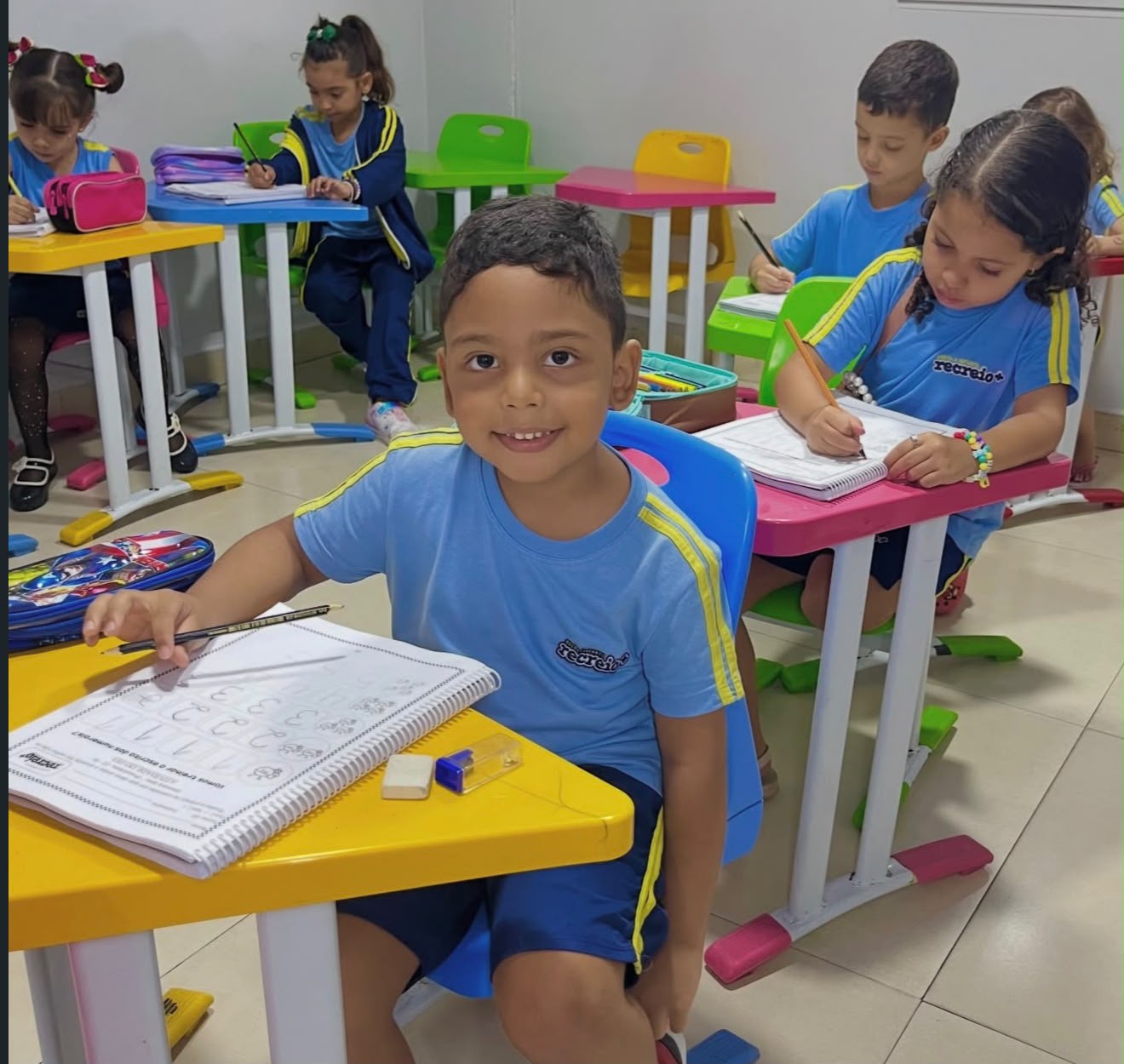 Aluno sorrindo durante atividade de escrita em sala de aula